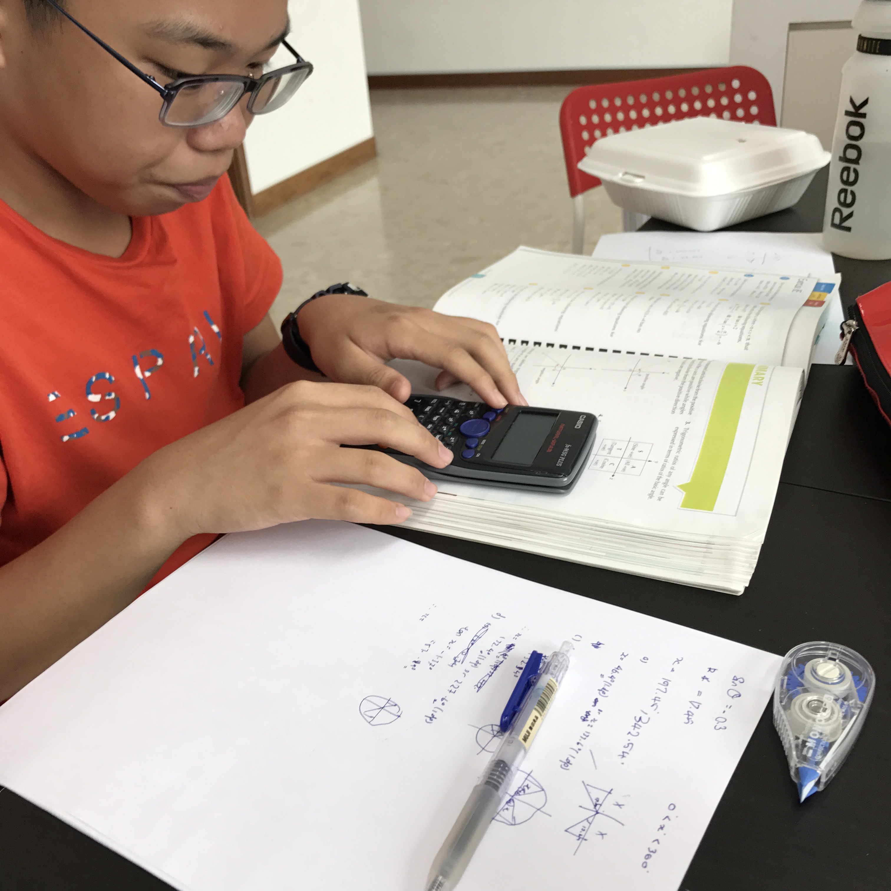 A student working on Additional Mathematics trigonometry exercises during tuition.