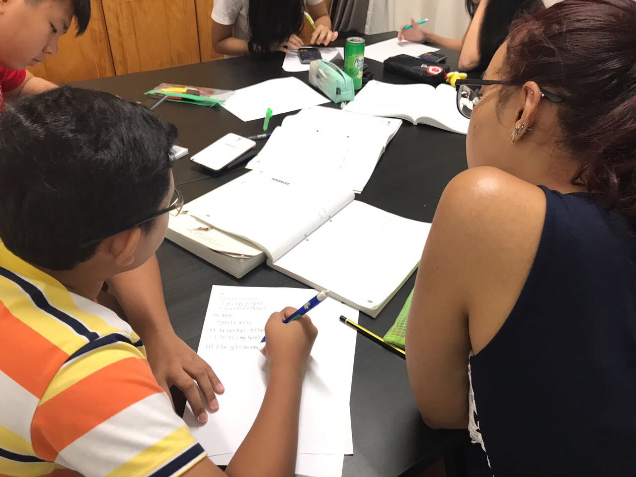 A tutor reviewing mathematics exercises during a small-group tuition class.
