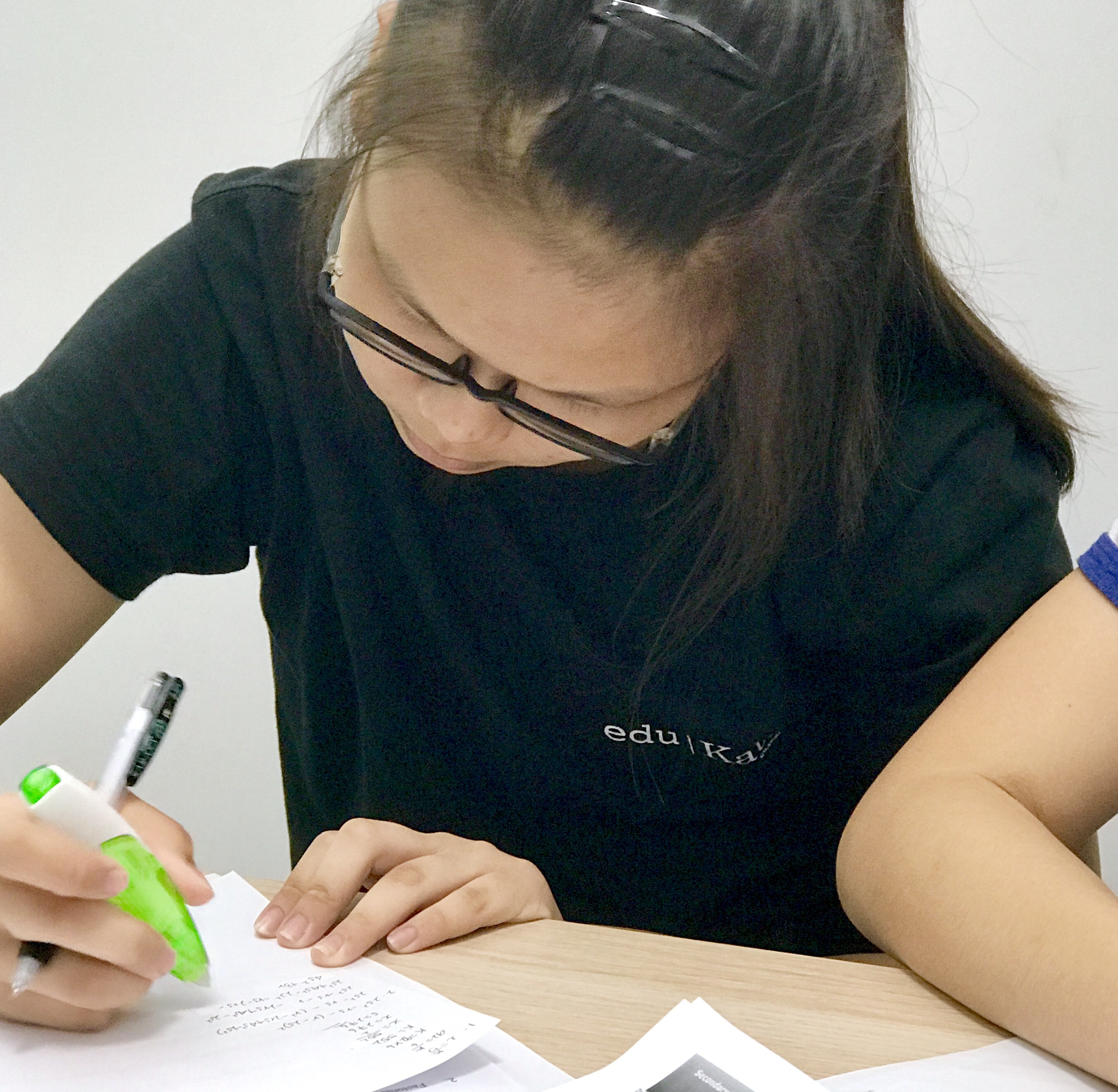 Tutor reviewing students' Mathematics working step by step.