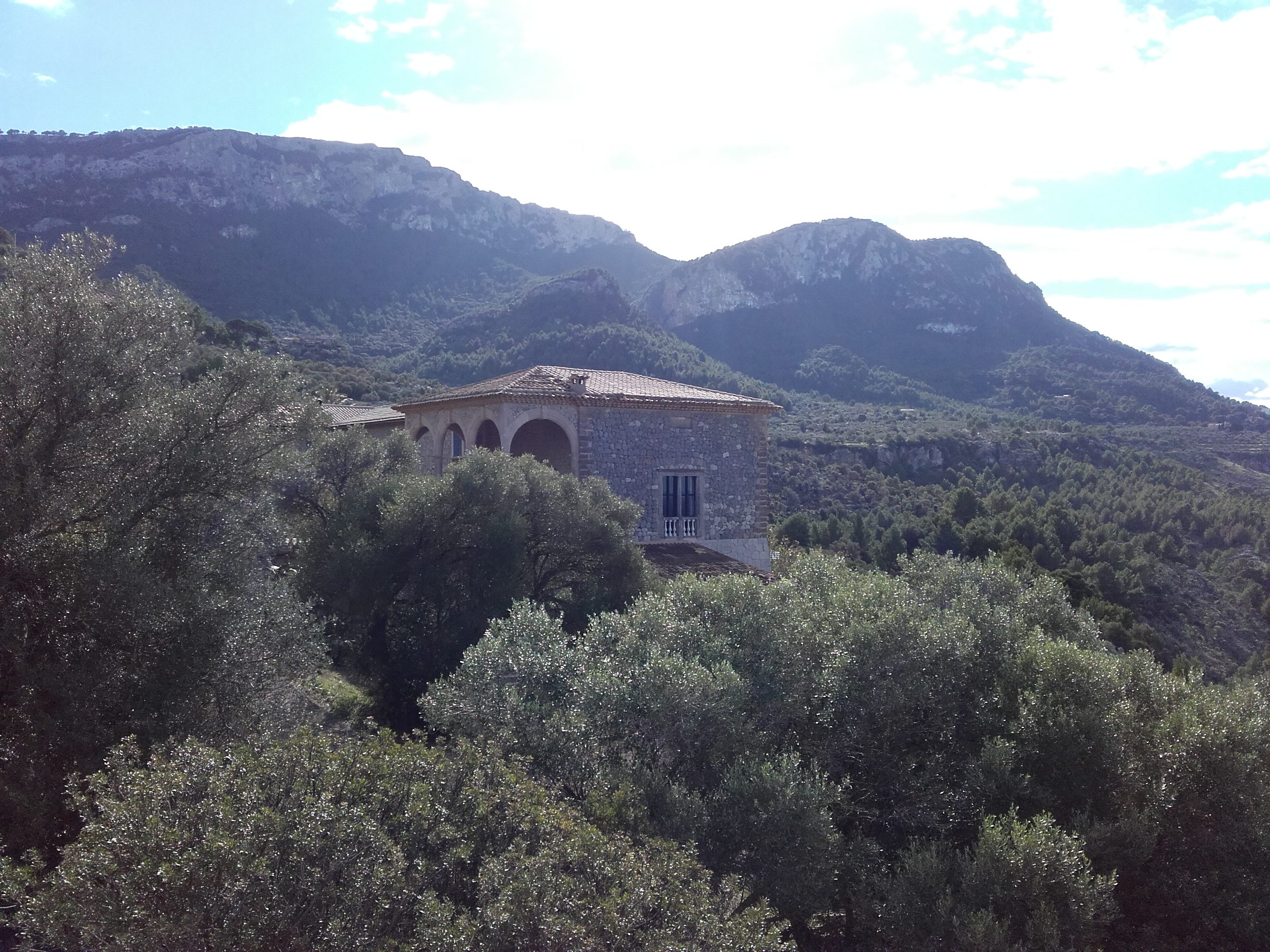 Stone estate building at Son Marroig in the Serra de Tramuntana mountains near Valldemossa, Mallorca, surrounded by olive trees and wooded hills.