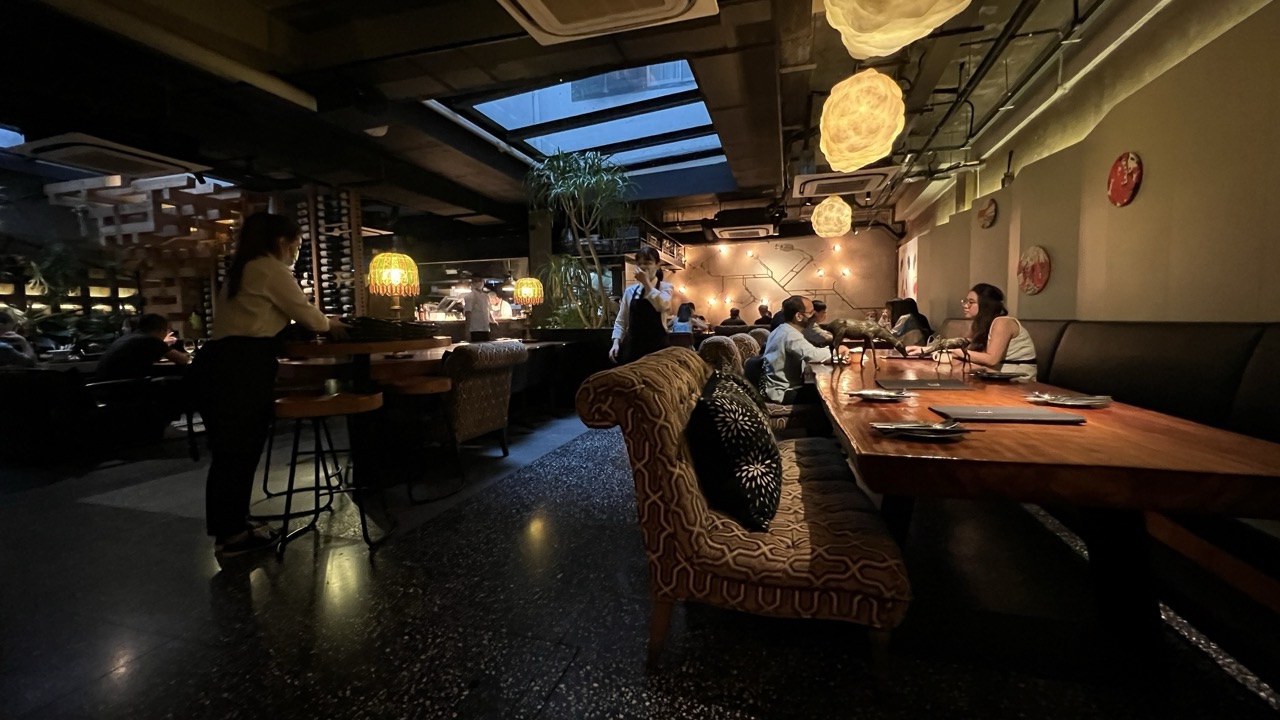 Restaurant interior in Singapore with diners and serving staff.