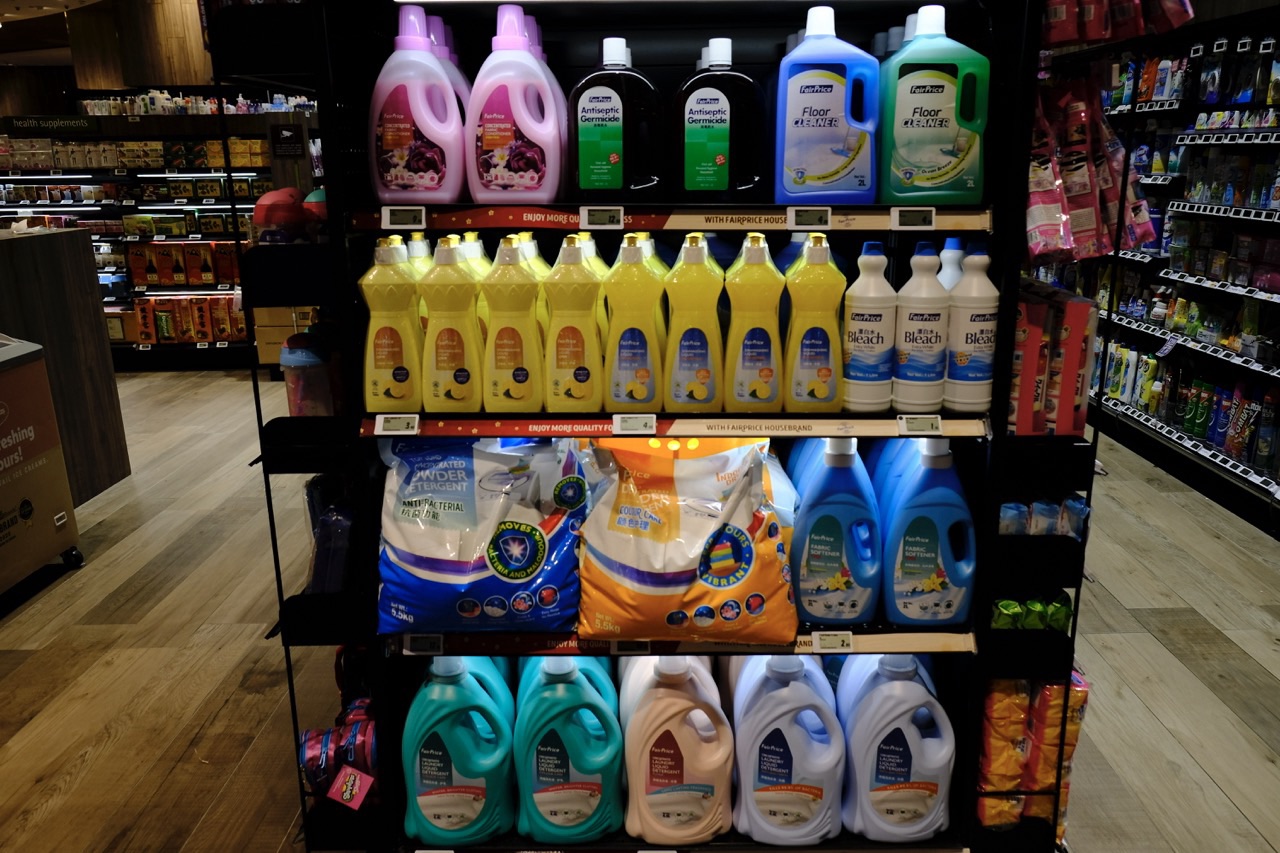 Laundry and household cleaning detergents displayed with price tags.