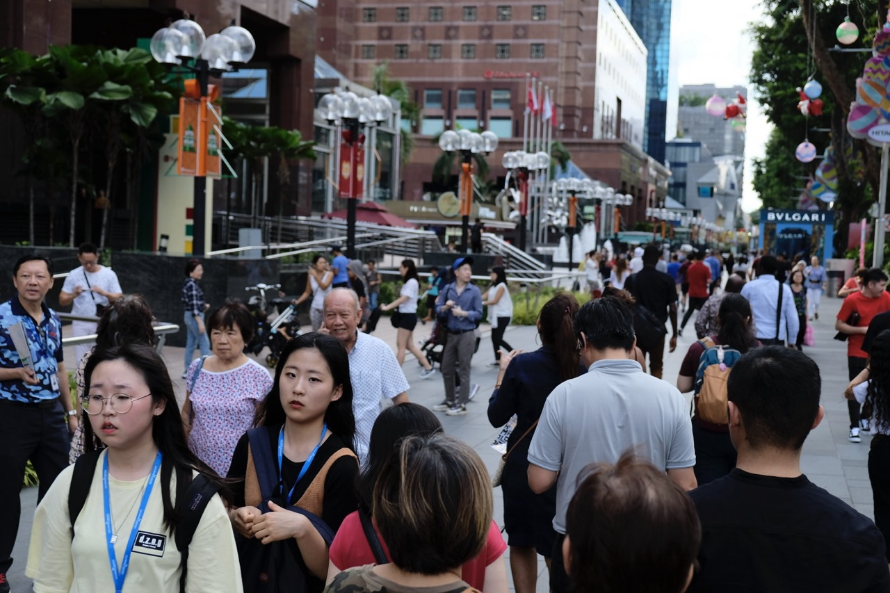 Large number of pedestrians along Orchard Road near Ngee Ann City in Singapore.