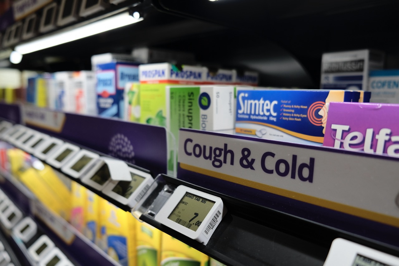 Cough and cold medicine displayed with a price tag on a retail shelf.