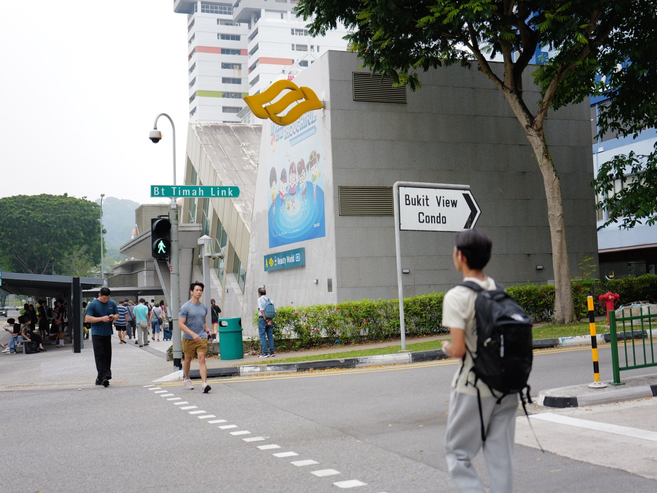 Pedestrians crossing Bukit Timah Link near a Beauty World MRT station exit.