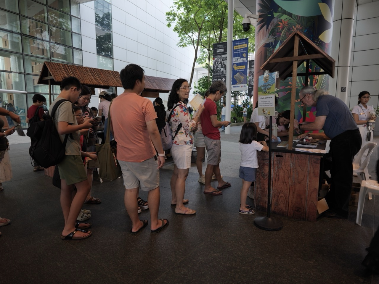 Visitors queuing beside an exhibition display outside the National Library Building in Singapore