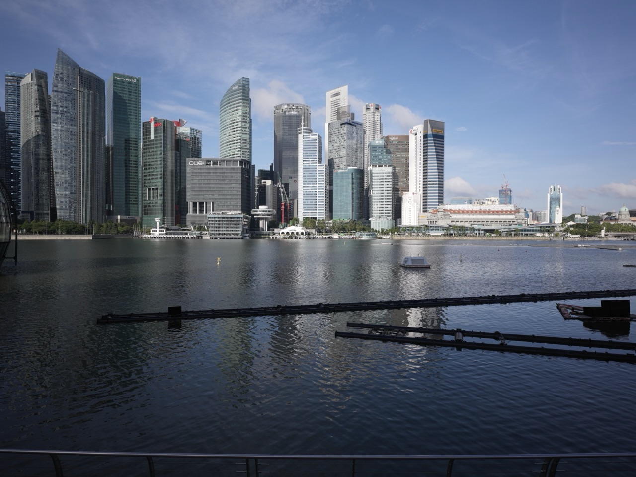 Waterfront promenade outside The Shoppes at Marina Bay Sands with the Marina Bay and Shenton Way financial district skyline