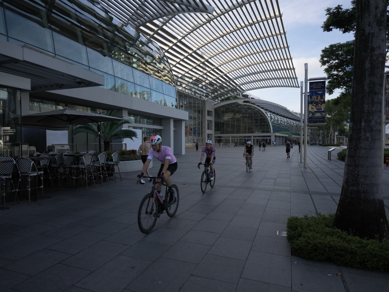 Group of cyclists on the waterfront promenade outside The Shoppes at Marina Bay Sands with the financial district skyline behind