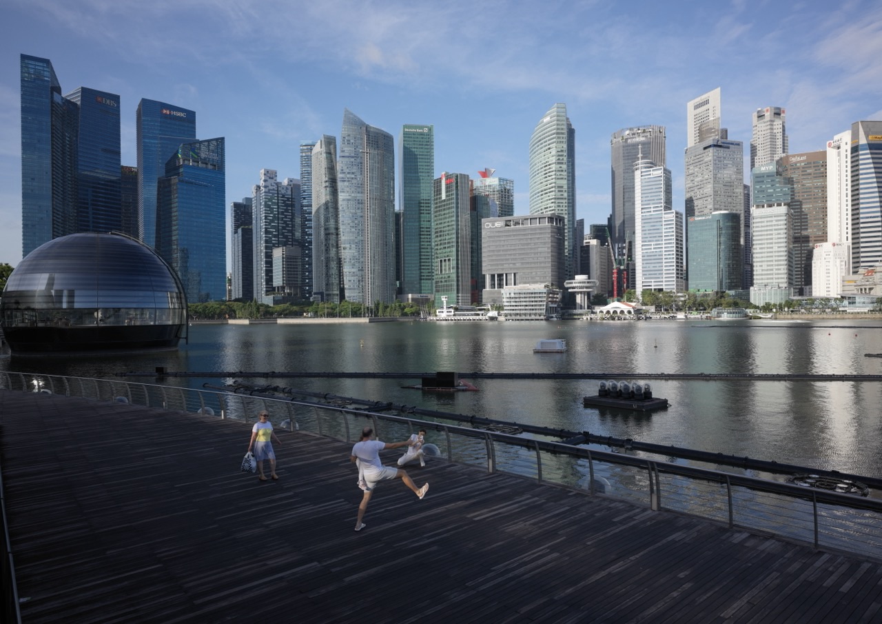 Family and tourists enjoying a photo session on the Marina Bay waterfront with the financial district skyline behind