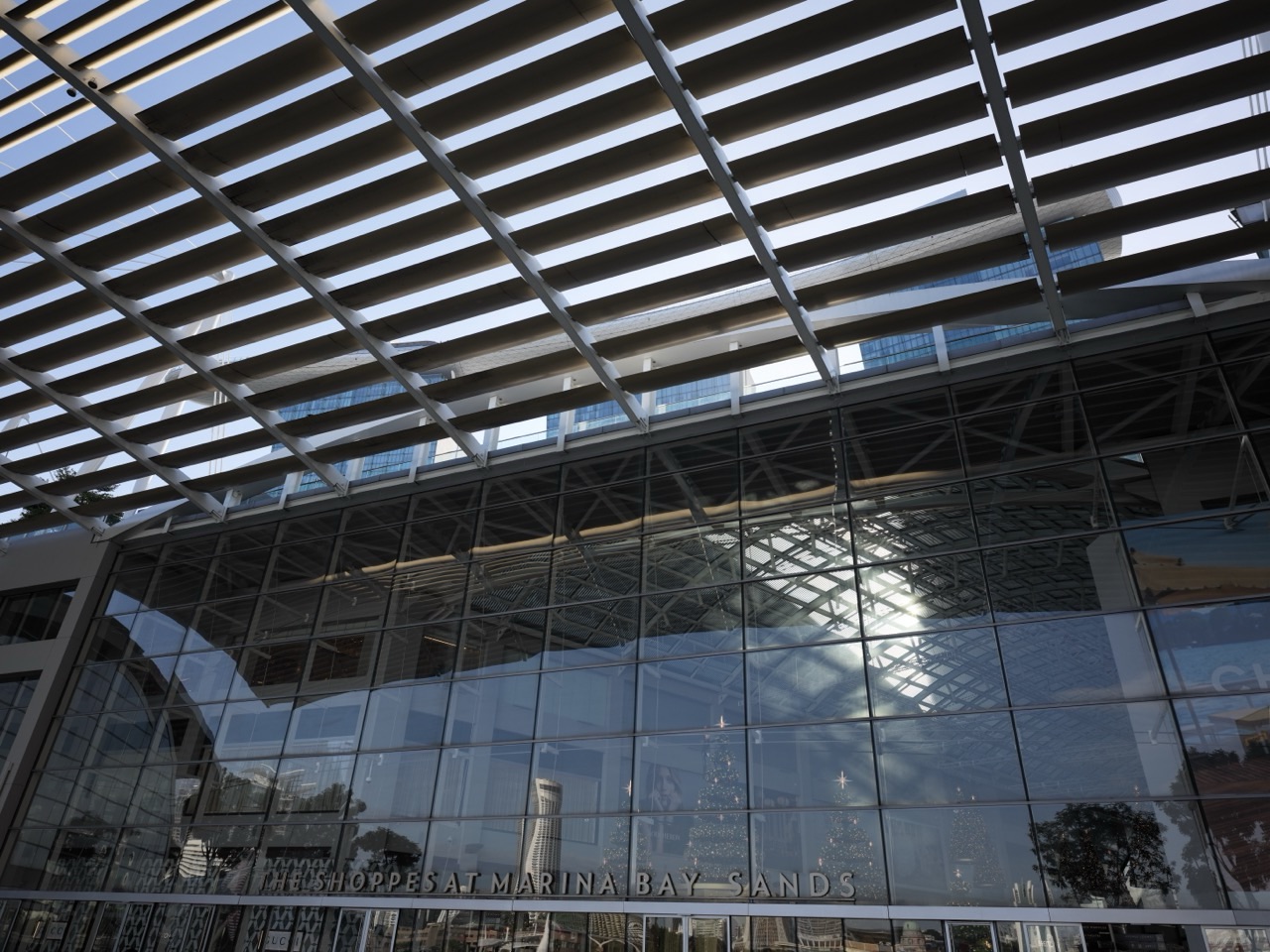 Glass architecture outside The Shoppes at Marina Bay Sands with the hotel towers in the background