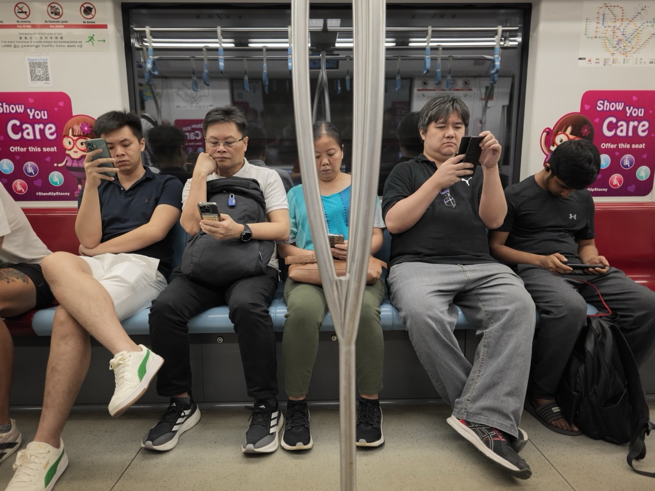 Seated passengers using smartphones inside a Singapore MRT train
