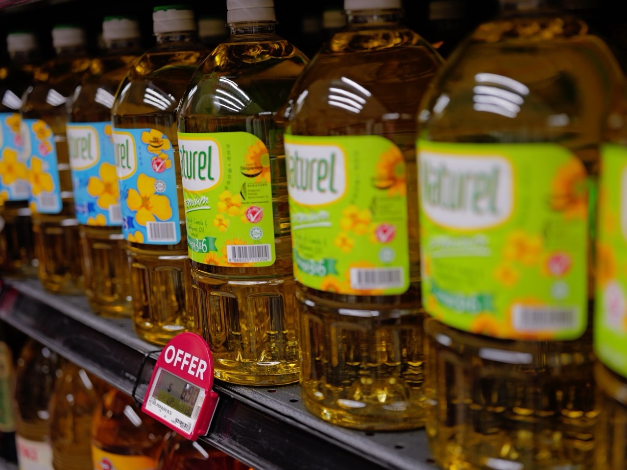 Bottles of cooking oil displayed on a supermarket shelf.