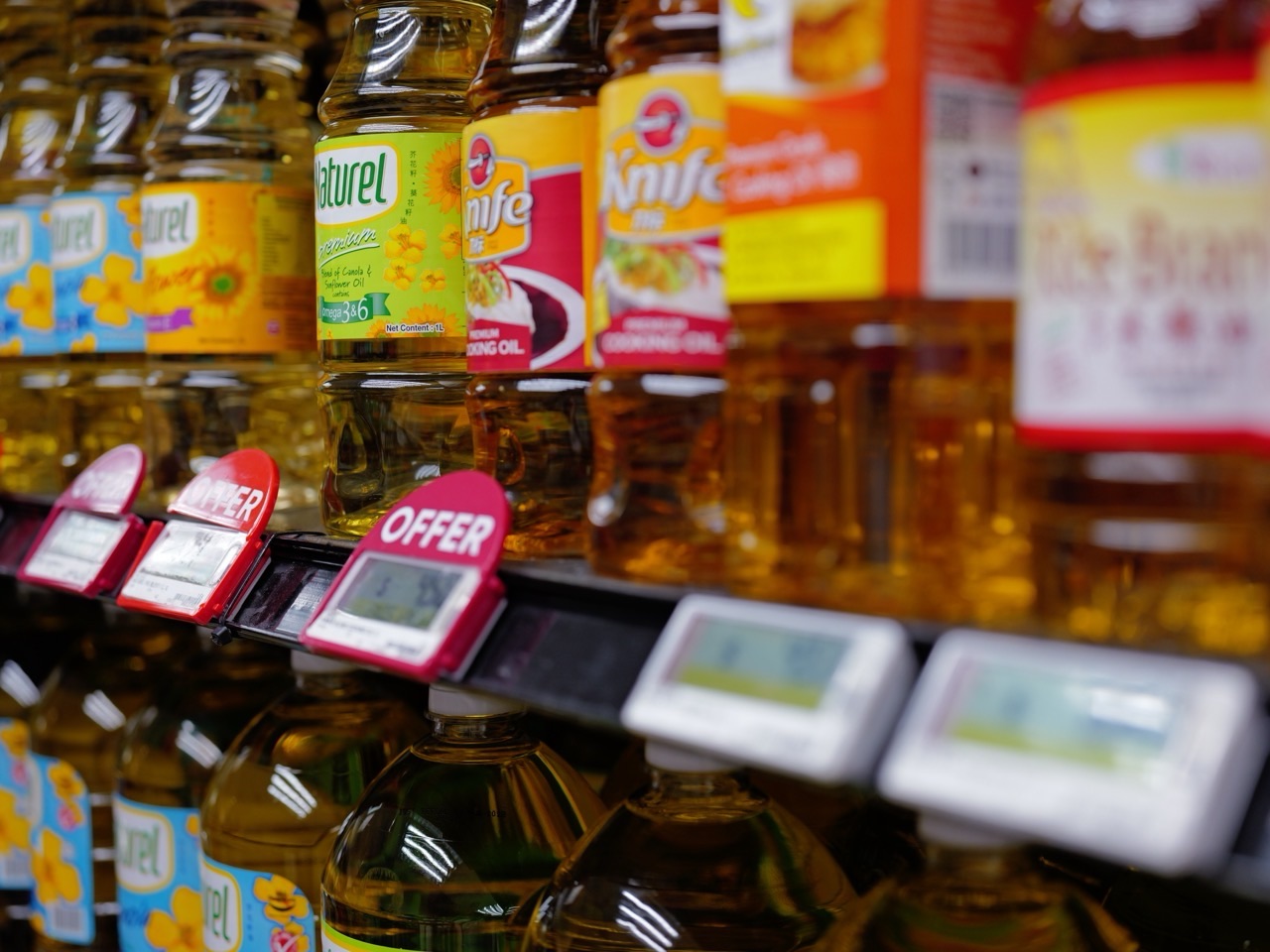 Bottles of cooking oil displayed on a supermarket shelf with visible prices.