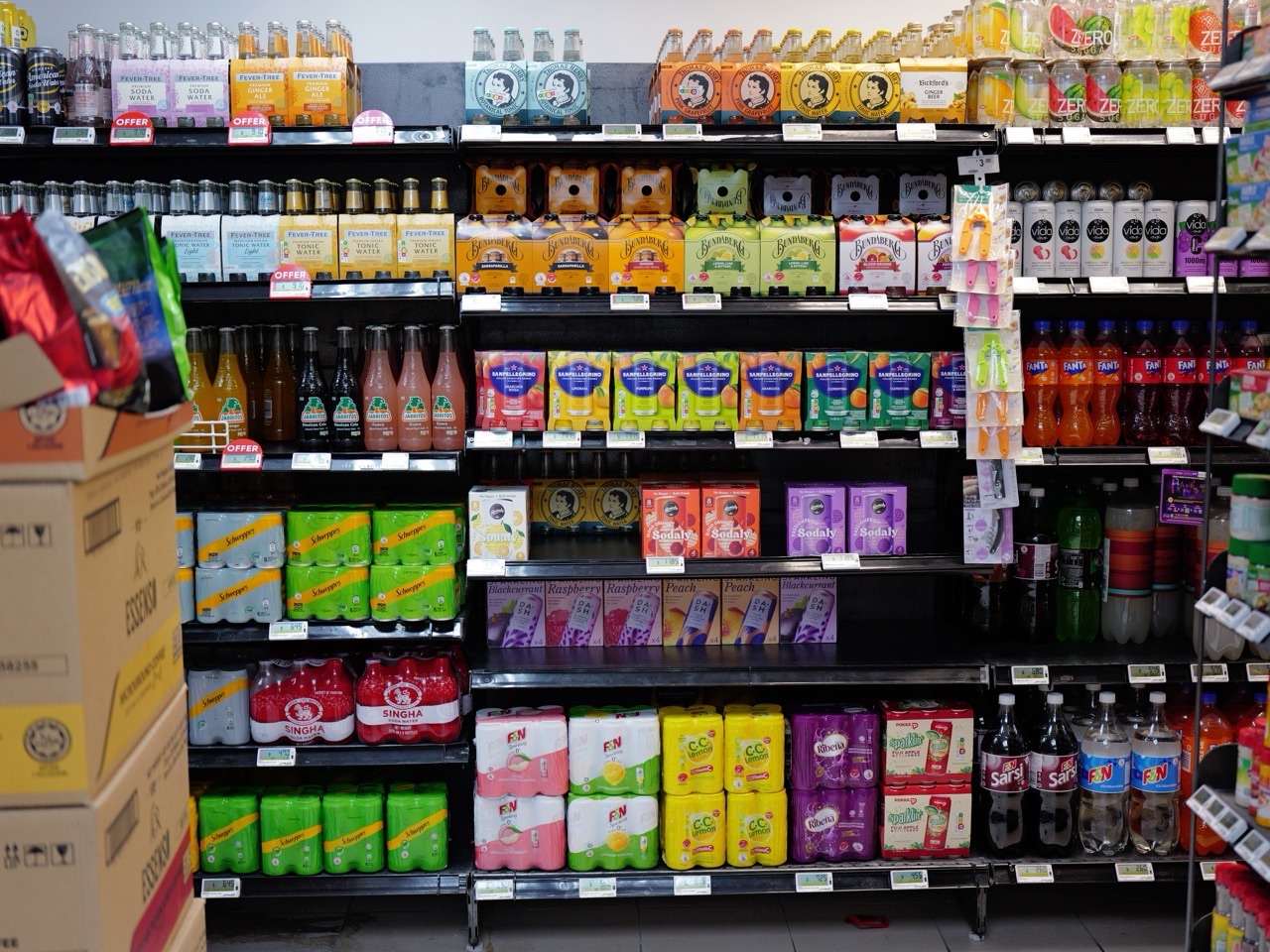 Soft drinks displayed on a supermarket shelf with visible prices.
