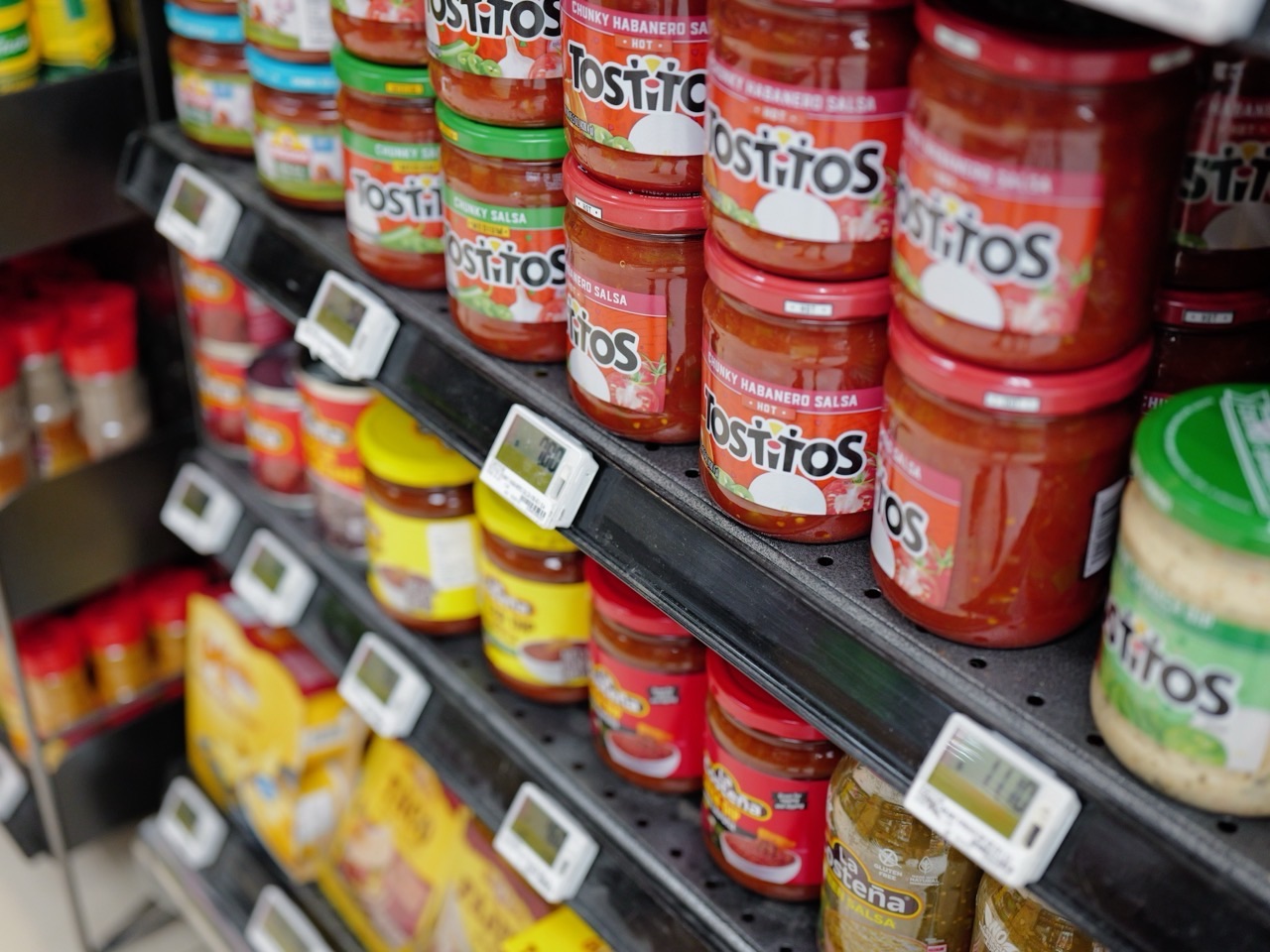 Salsa in glass jars displayed on a supermarket shelf with a visible price label.