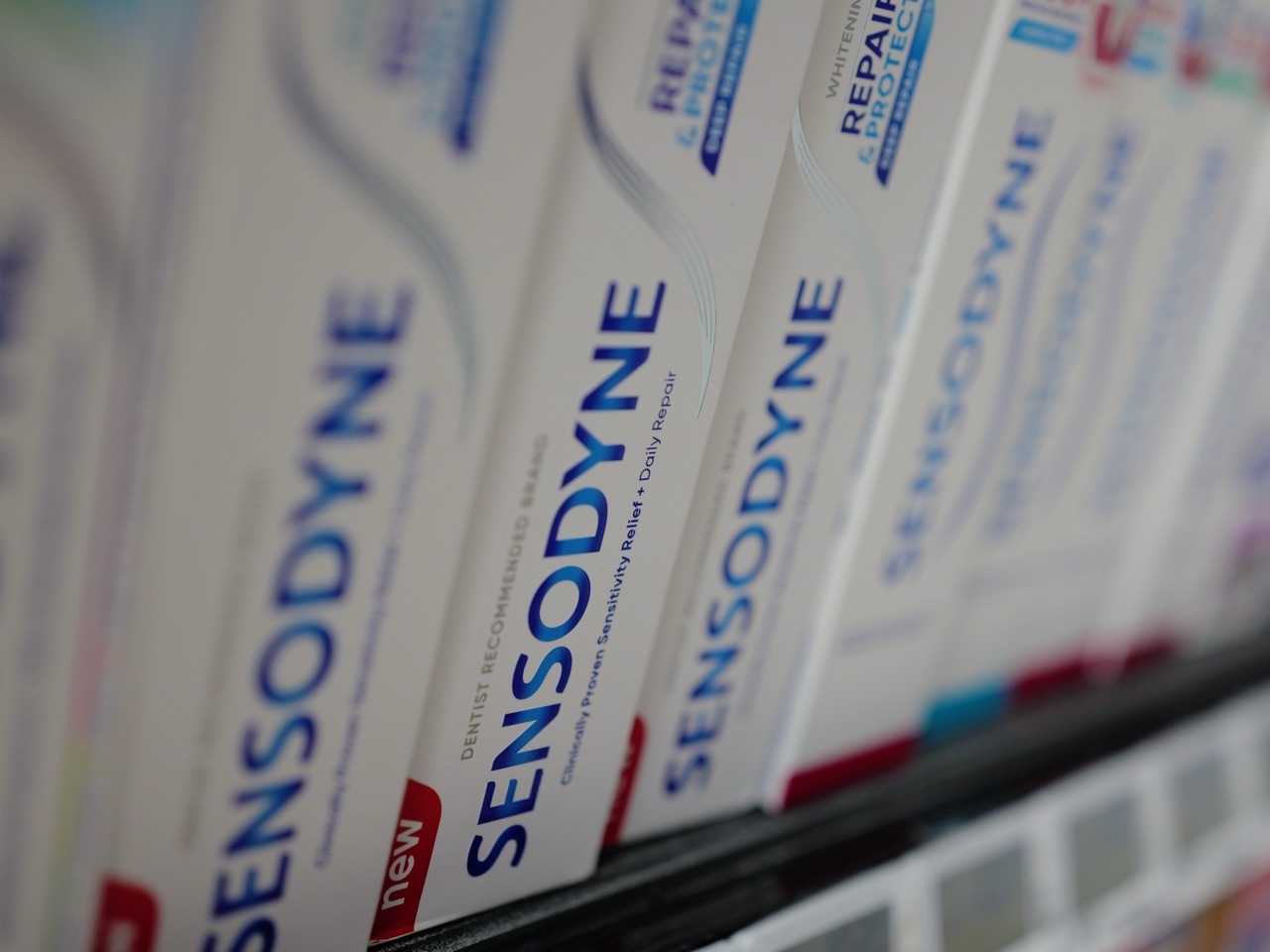 Toothpaste products displayed on a supermarket shelf.