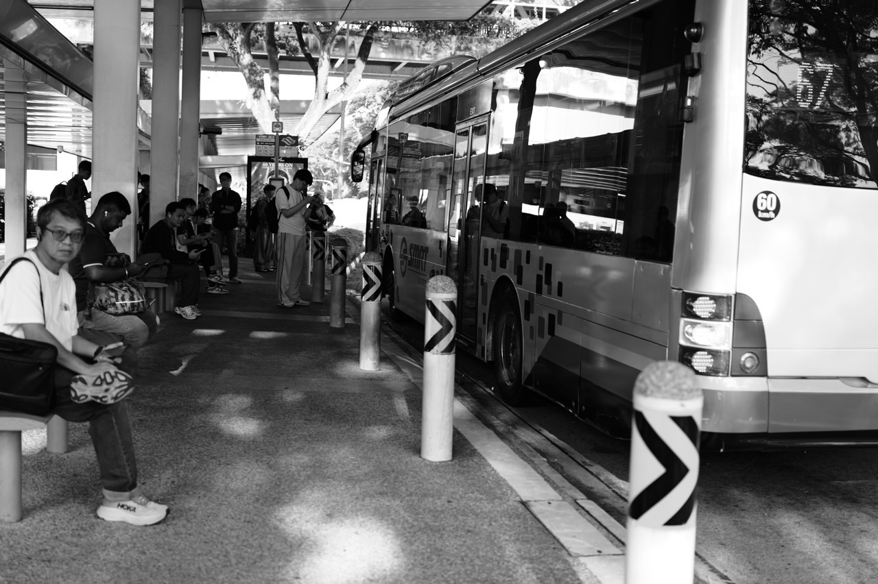 Bus and waiting passengers at a bus stop outside Sixth Avenue MRT station in Bukit Timah, Singapore.