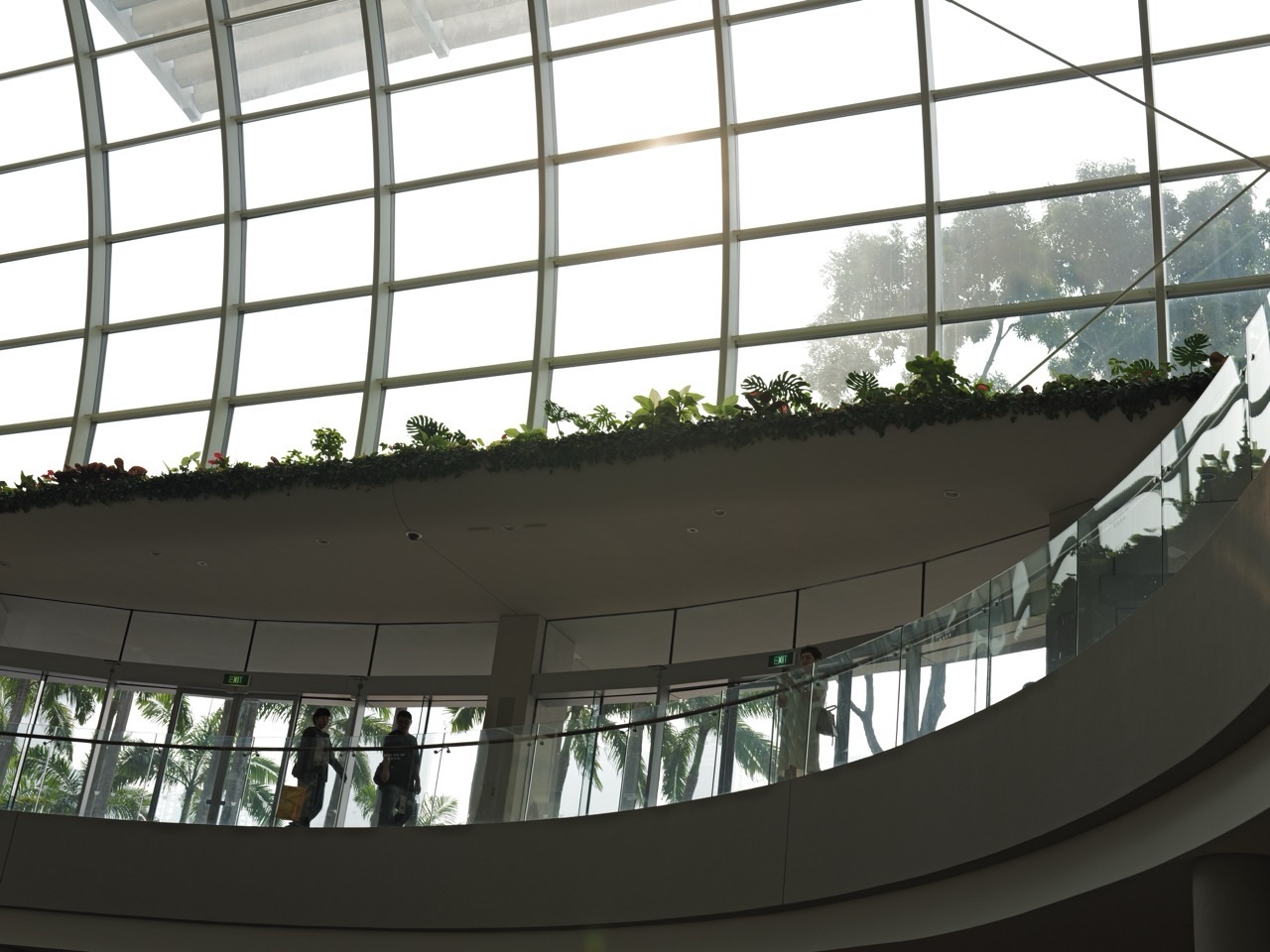 Roof detail and silhouetted shoppers on the left at Marina Bay Sands, with a hazy view outside.