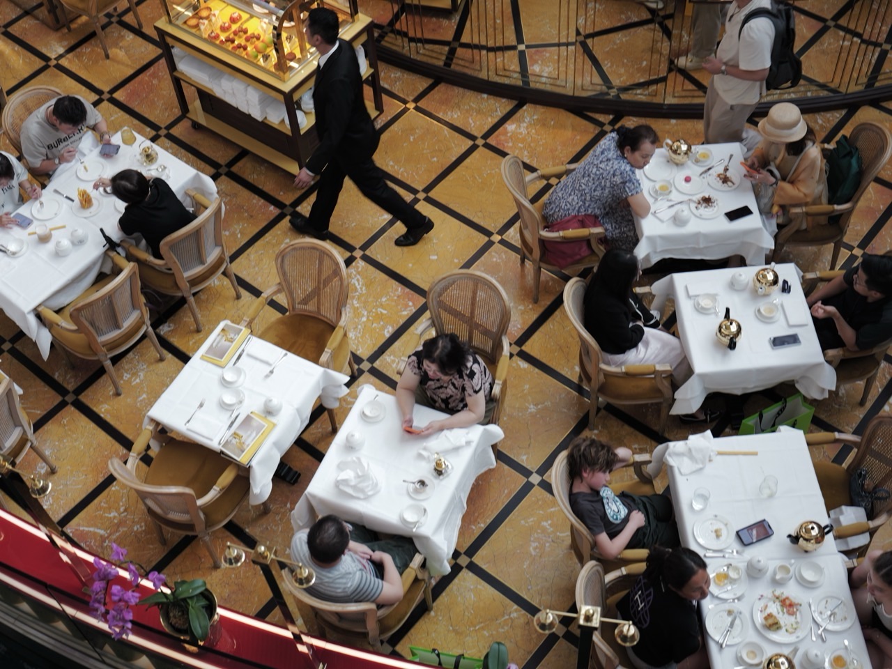 Overhead view of staff serving diners who are eating and talking at a Marina Bay Sands restaurant.