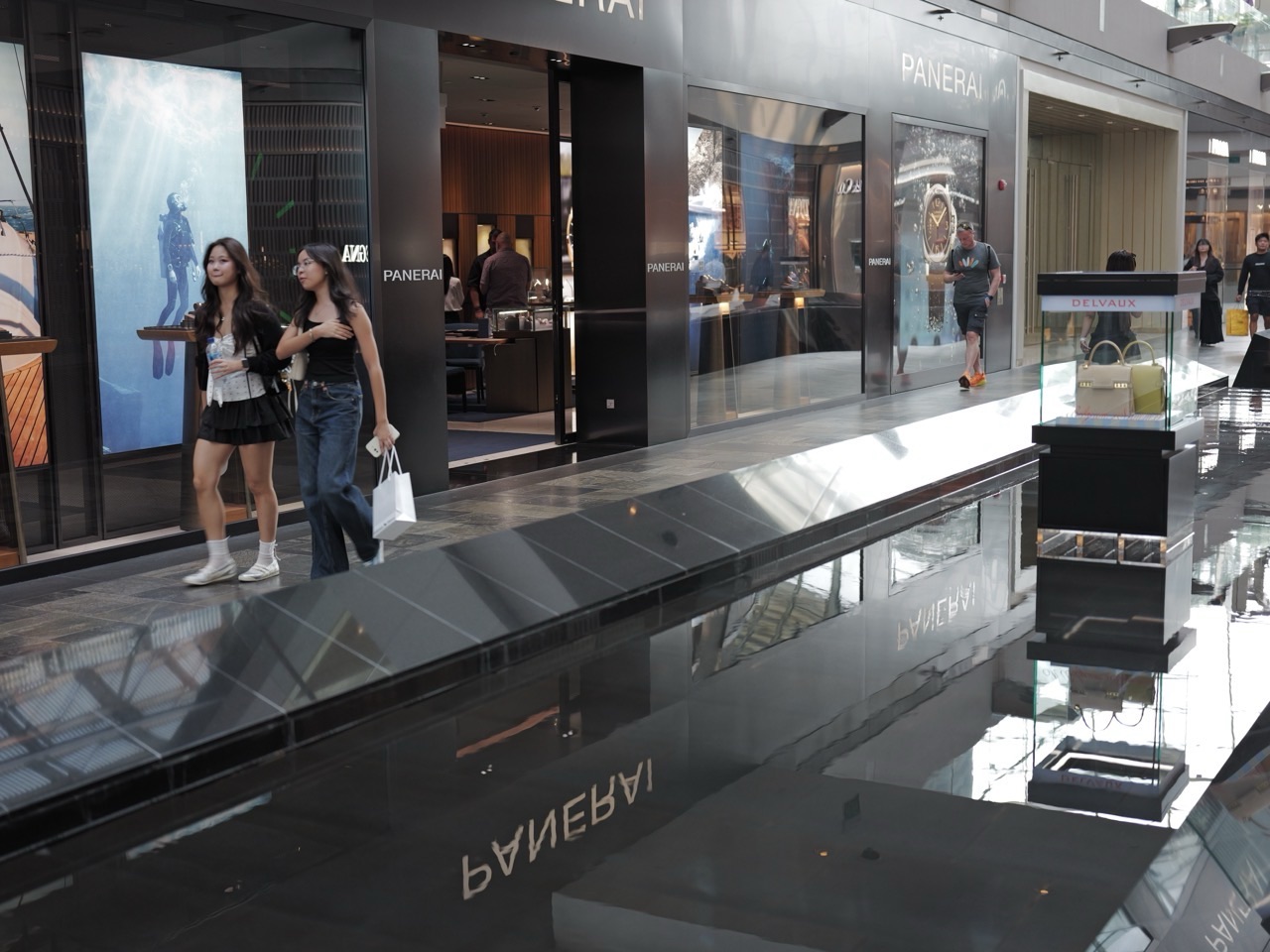 Two shoppers beside an indoor walkway and water feature at The Shoppes at Marina Bay Sands.
