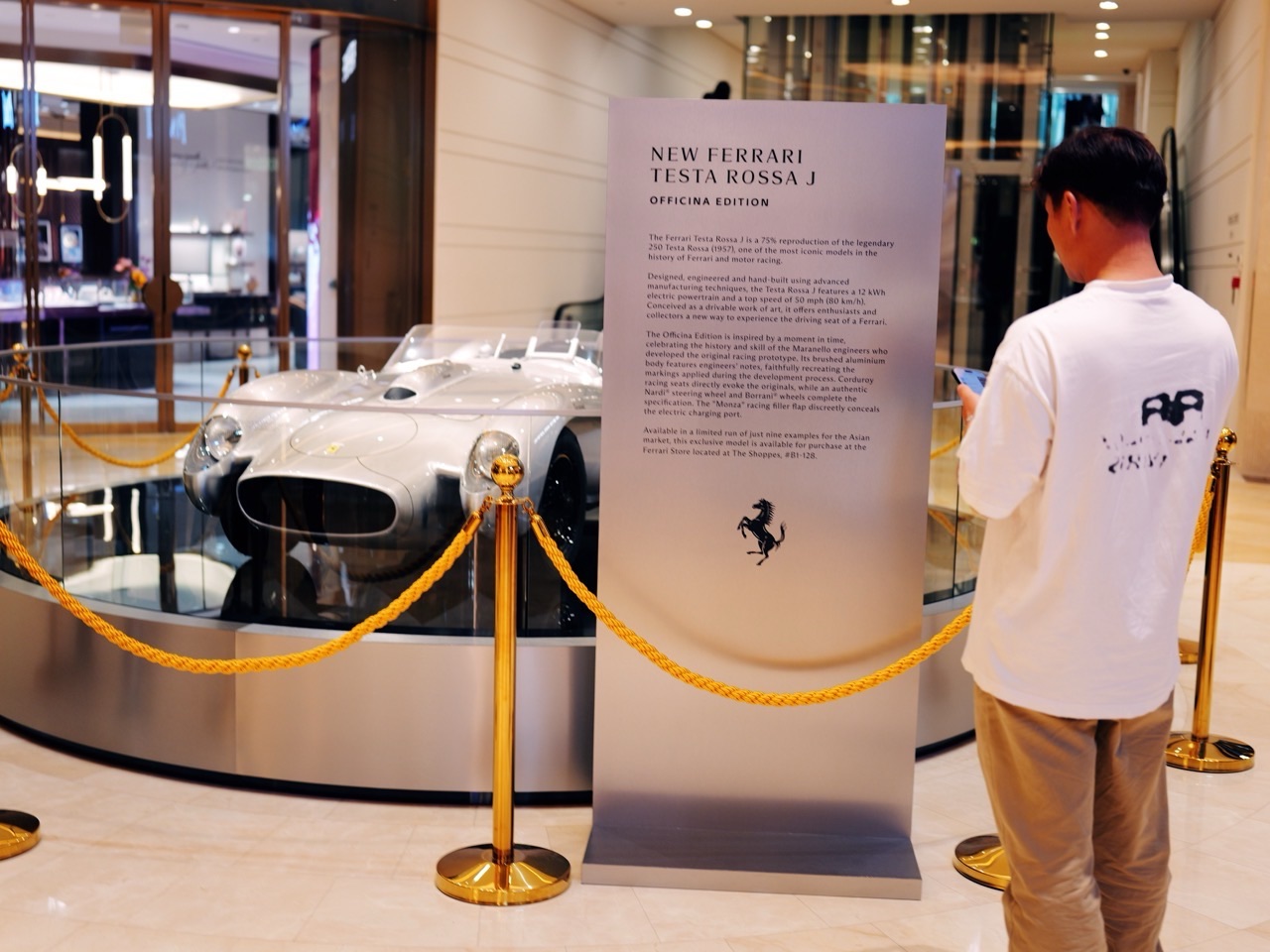 Visitors reading information beside a miniature Ferrari display at The Shoppes at Marina Bay Sands.