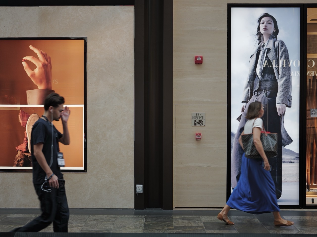 Two pedestrians beside large retail advertisements at Marina Bay Sands, Singapore.