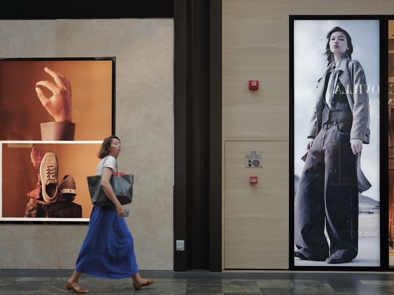 A visitor walking beside a large shop advertisement at Marina Bay Sands, Singapore.