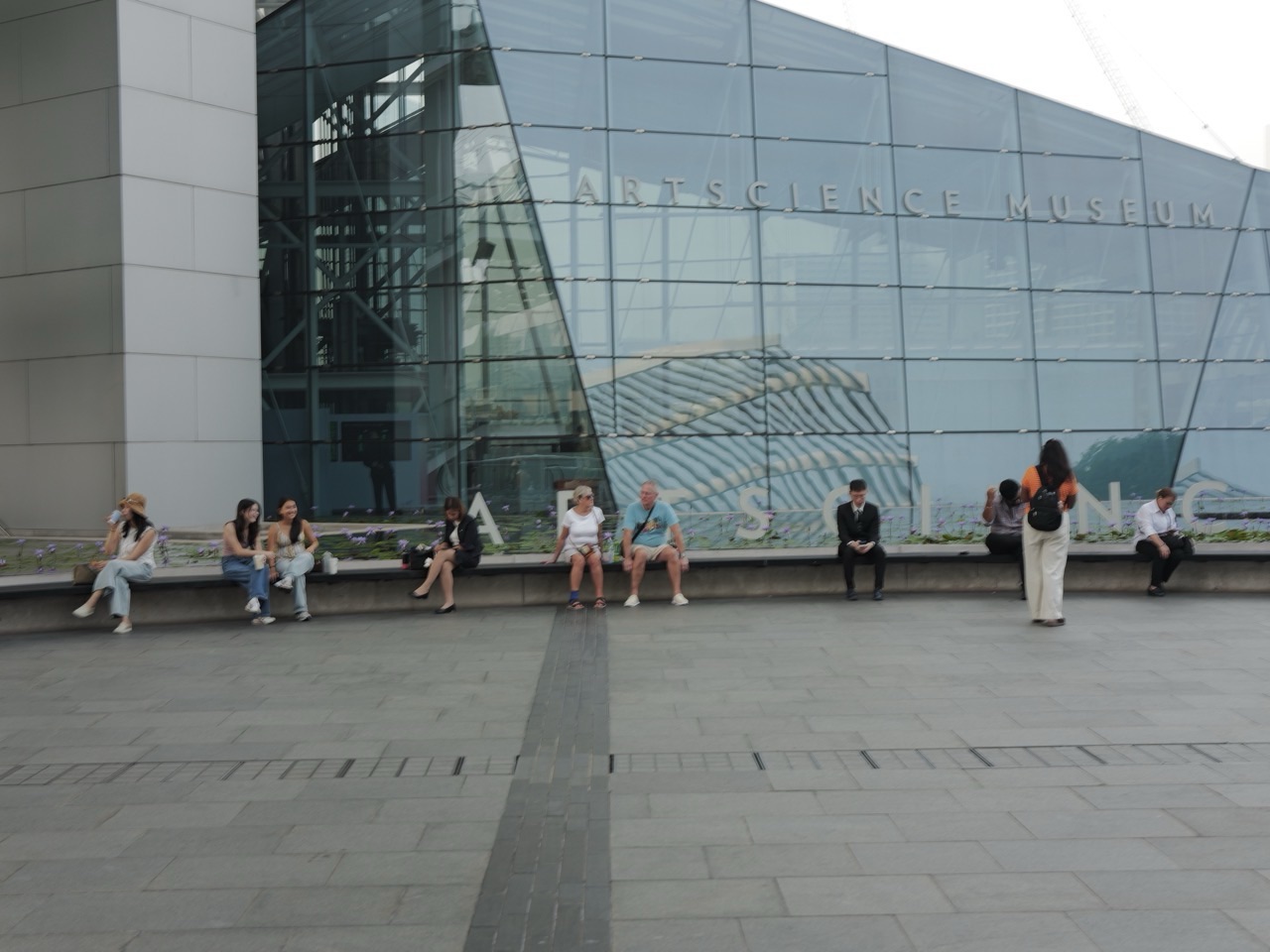 Visitors relaxing in outdoor seating beside ArtScience Museum at Marina Bay Sands.