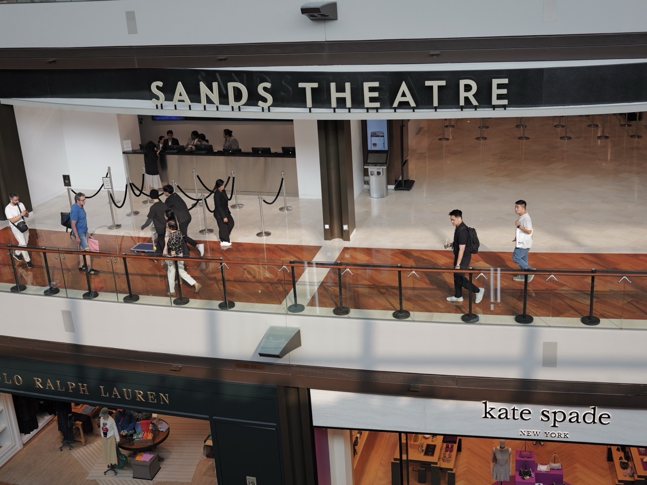 Shoppers passing Sands Theatre at Marina Bay Sands, with a counter visible inside.