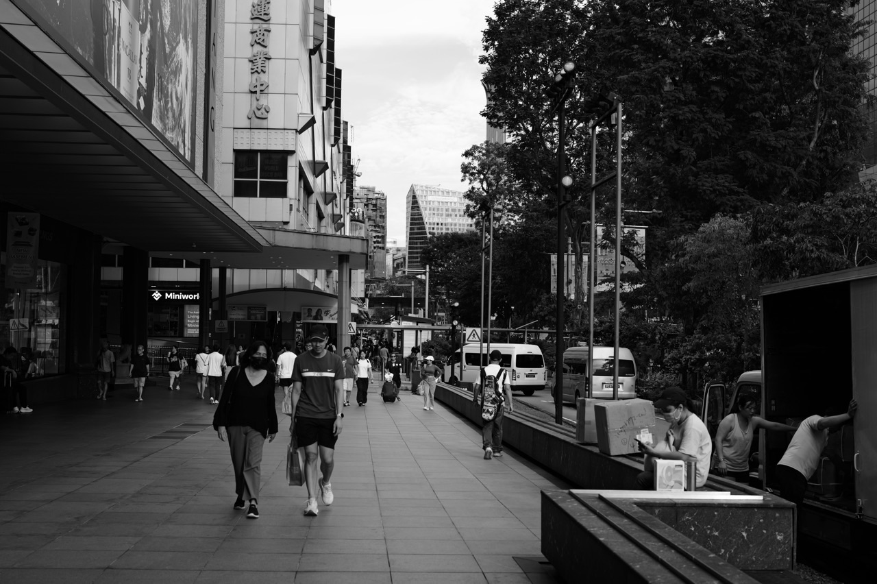 Pedestrian walking outside TANGS on Orchard Road with delivery activity on the left.