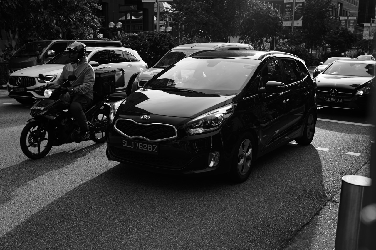 Car and motorcycle travelling along Orchard Road in Singapore.