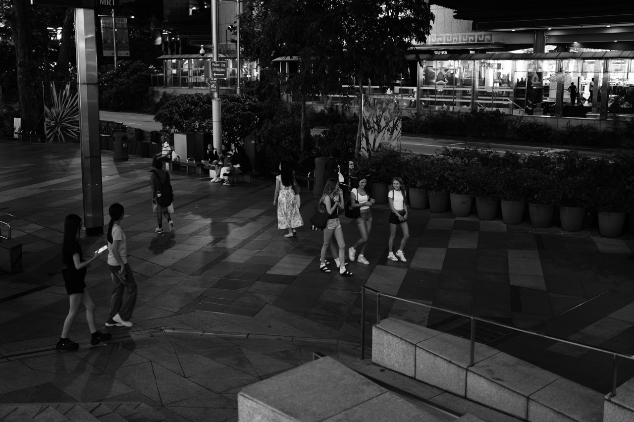 Shoppers and pedestrians walking along Orchard Road at night in Singapore.