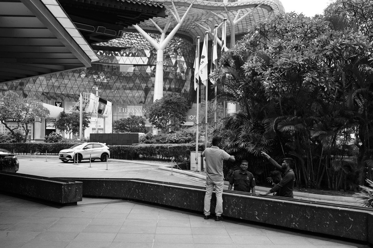 Workers outside TANGS on Orchard Road with ION Orchard and a valet parking area in view.