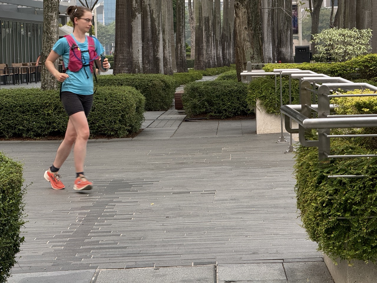 Woman running with a hydration vest outside Marina Bay Sands in Singapore.
