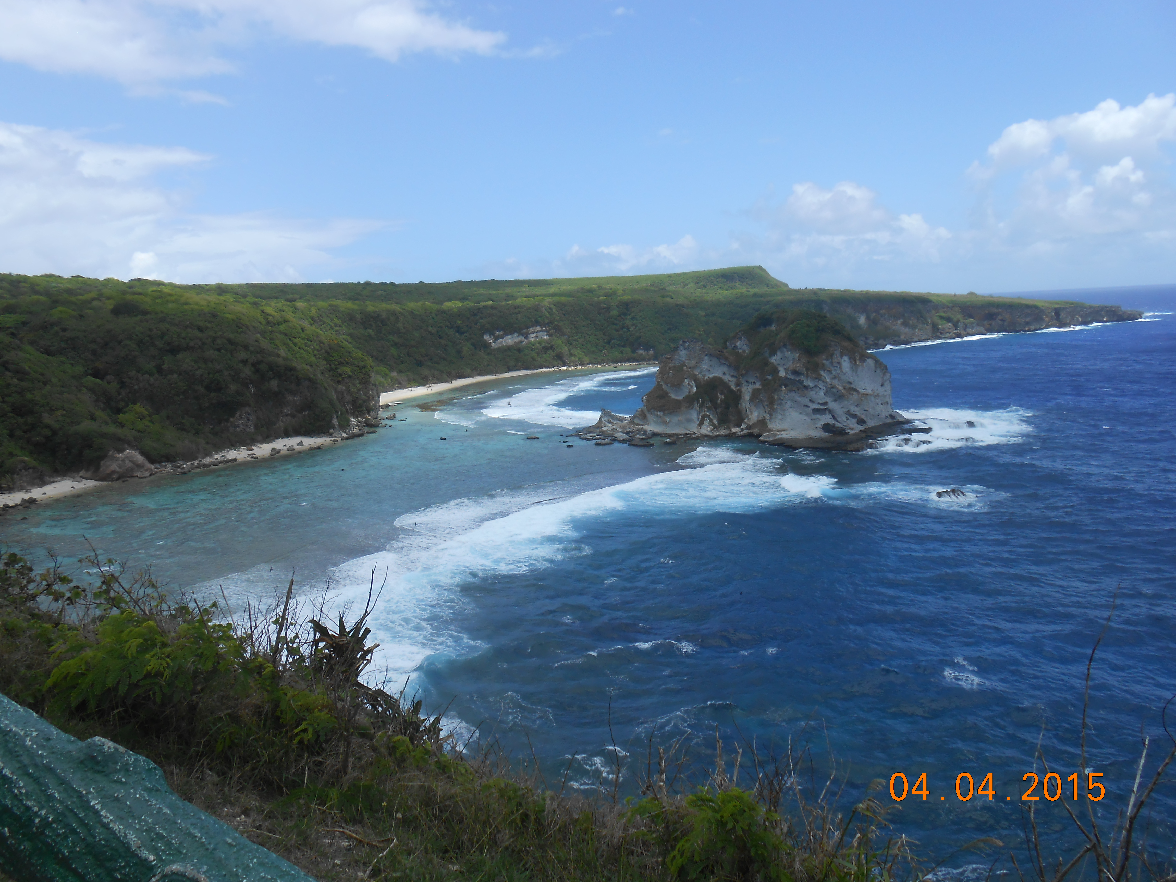 Bird Island on Saipan's northeastern coast, a small vegetated limestone islet surrounded by blue Pacific water.