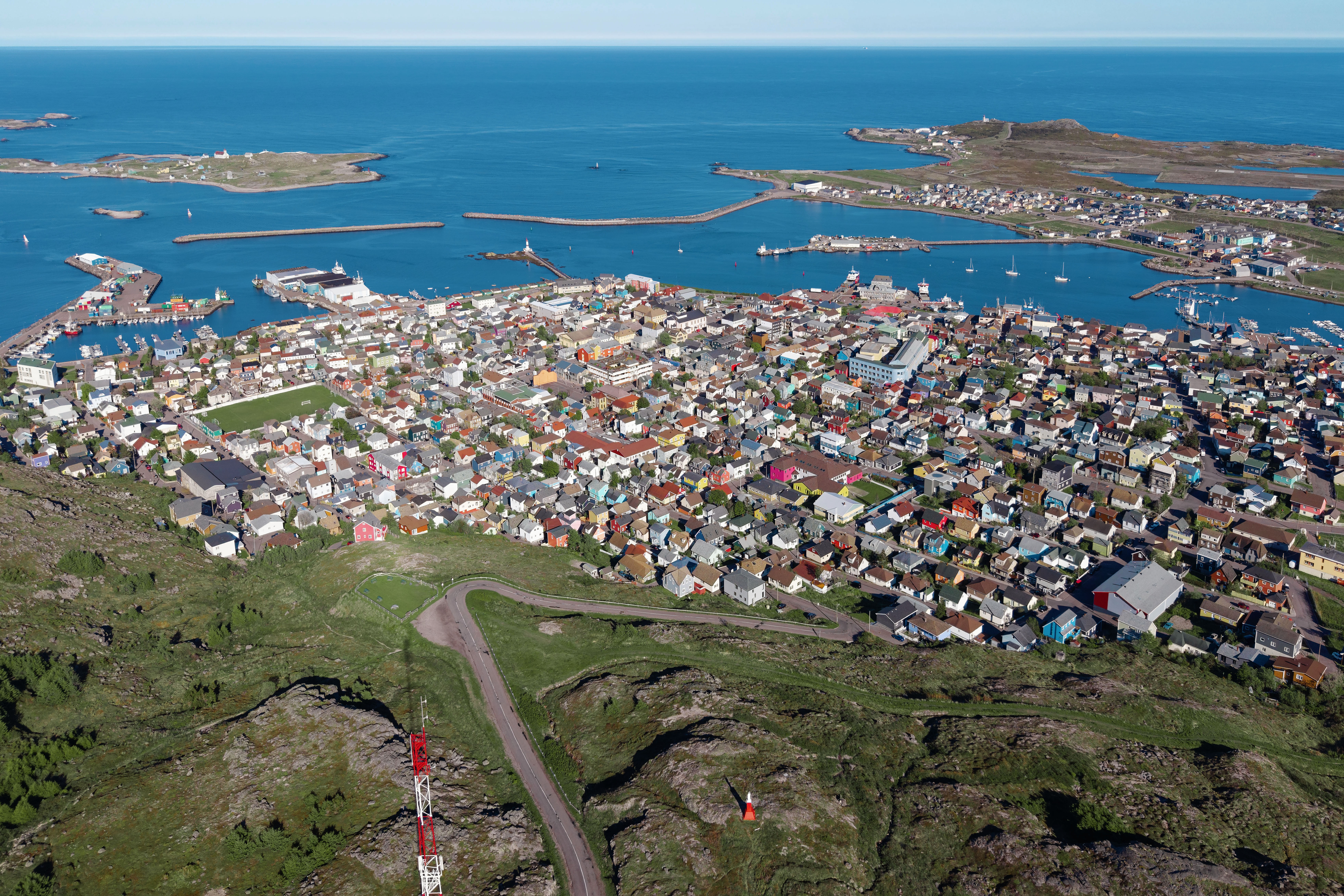 View over Saint-Pierre town and harbour with colourful rooftops, steep coastal hills and the North Atlantic on Saint Pierre and Miquelon in 2026.