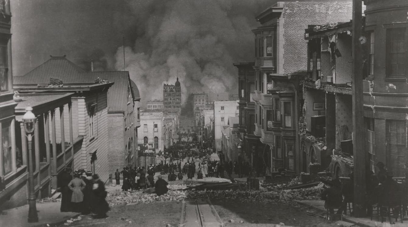 Arnold Genthe's 1906 photograph looking down Sacramento Street toward smoke rising from fires after the San Francisco earthquake, with damaged buildings and people in the street.