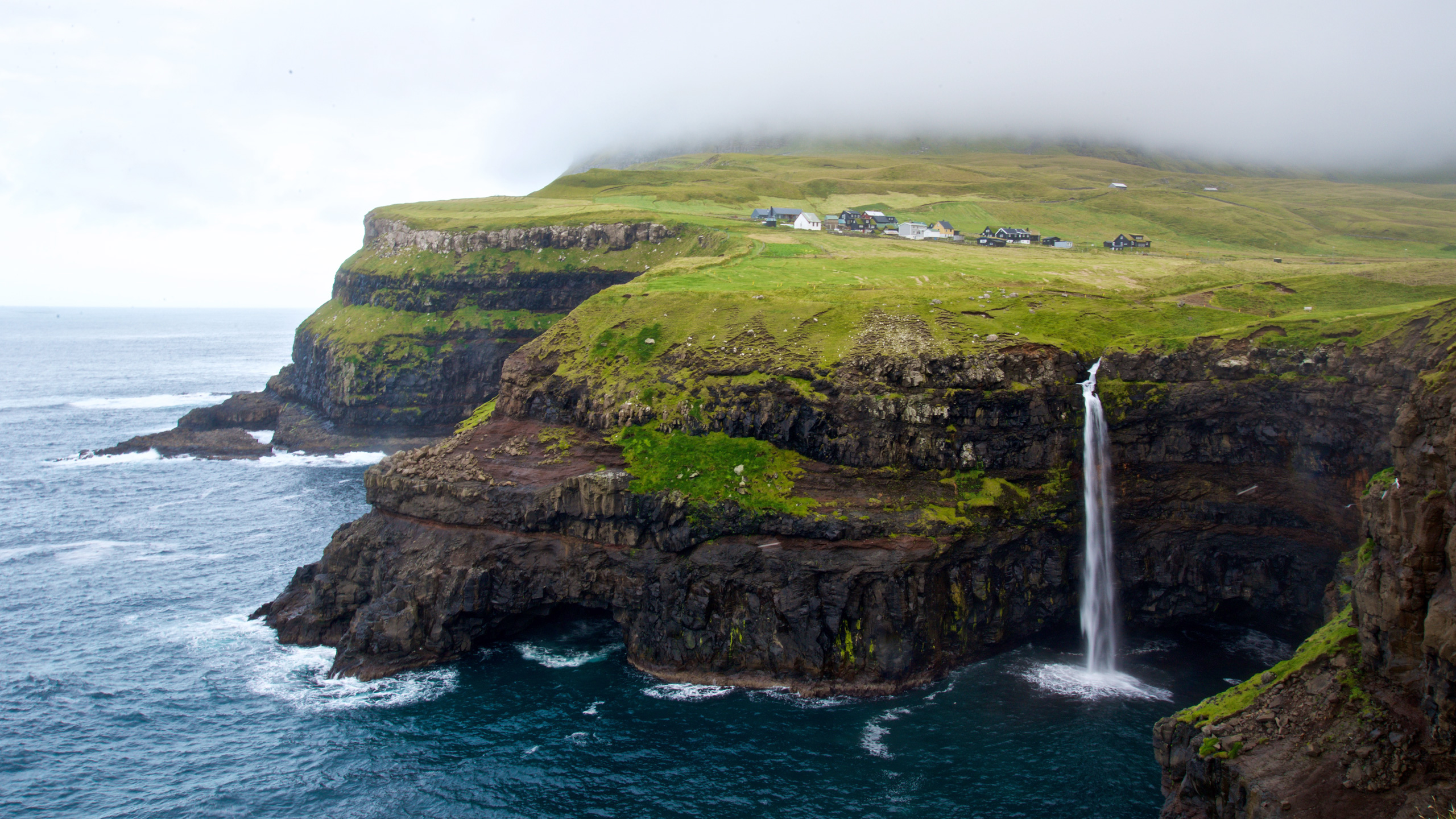 Múlafossur waterfall plunging from a grassy Faroe Islands cliff into the North Atlantic beside Gásadalur village on Vágar